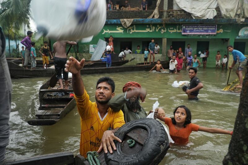 People wade through flood water to collect food aid after heavy monsoon rainfall in Companiganj, Bangladesh. AFP