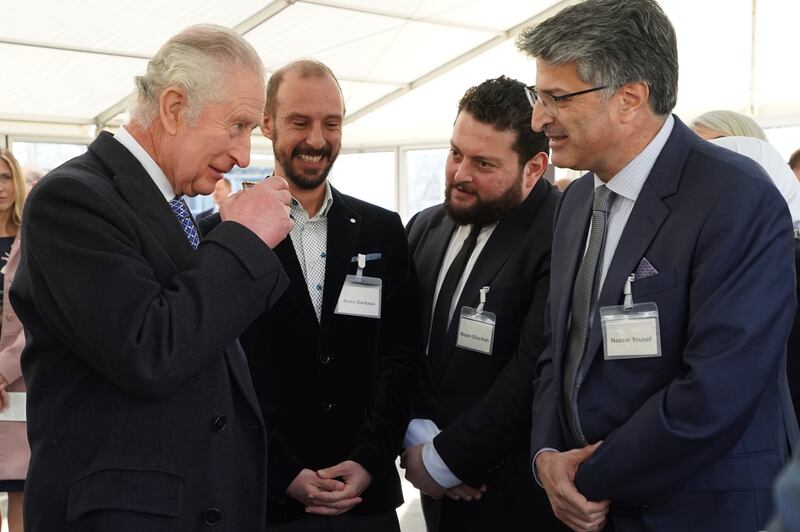 King Charles takes a sip of Syrian tea as he talks with members of the Syrian community. AP