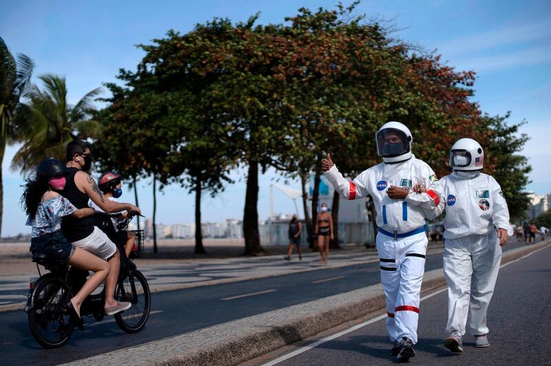 Brazilian accountant Tercio Galdino, 66, gives the thumb up to people riding a motorcycle as he and his wife Alicea Galdino walk along Leme beach in protective suits, in Rio de Janeiro, Brazil.  Tercio, who has a chronic lung disease, made the protective suits (looking like astronauts gear) at home using suits used by health professionals. He says that, in addition to giving him protection against the new coronavirus, they also wear them for fun, as he has huge interest in astronomy.  AFP