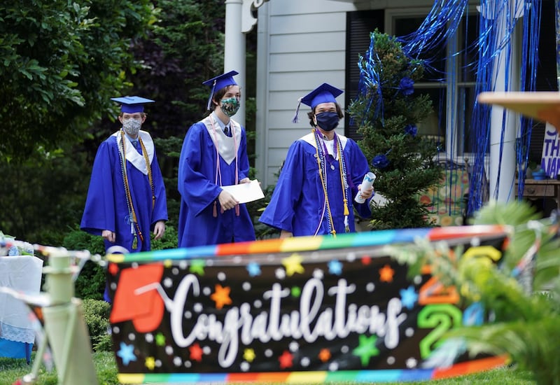 Bishop O'Connell High School graduates Michael Gallo, Daniel Cahill and Rafael Ruiz process during a front yard drive-in coronavirus honorary graduation ceremony at a home in Falls Church, Virginia, US. Reuters