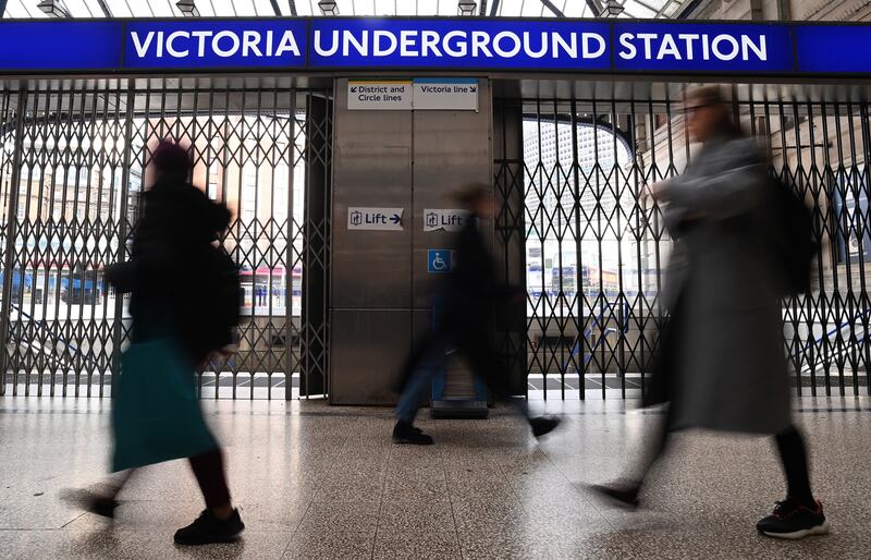 Commuters pass a closed Victoria Underground station in London. EPA