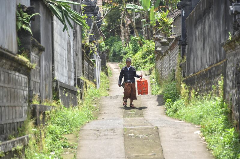 A villager carries his bird cage while leaving his village, in Sideman, where many villagers left for shelters due to Mount Agung volcanic activities, in Karangasem on Bali island on September 29, 2017. 
A rumbling volcano on the holiday island of Bali is spewing steam and sulphurous fumes with more intensity, heightening fears of an eruption as officials said the number of evacuees had topped 144,000. / AFP PHOTO / BAY ISMOYO