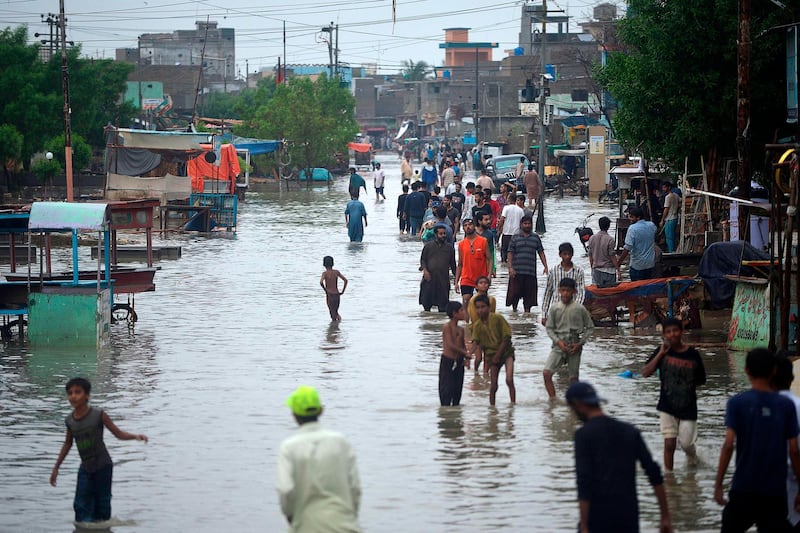 Residents wade through a flooded street after heavy monsoon rains in Pakistan's port city of Karachi.   AFP