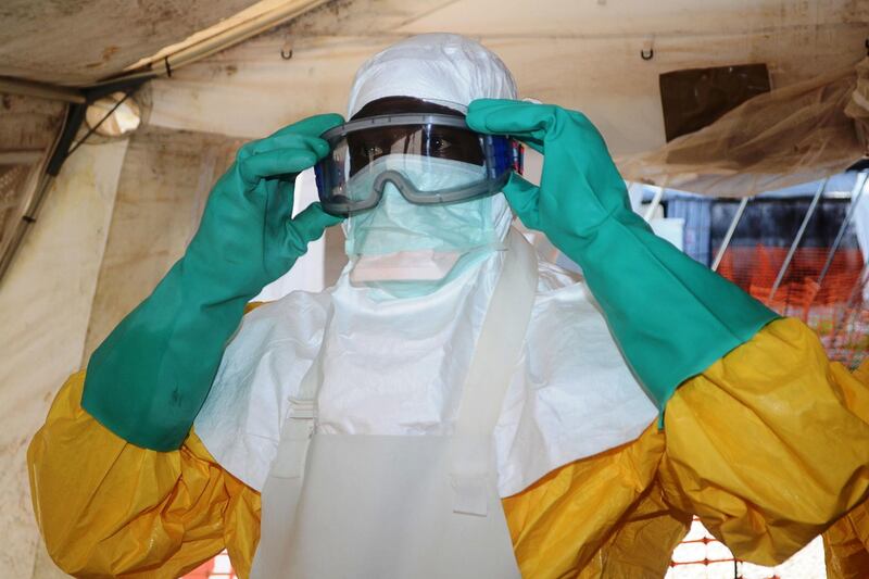 (FILES) This file photo taken on June 28, 2014 shows a member of Doctors Without Borders (MSF) putting on protective gear at the isolation ward of the Donka Hospital in Conakry, where people infected with the Ebola virus are being treated.  Four people have died of Ebola in Guinea, the first resurgence of the haemorrhagic fever in the West African nation since a 2013-2016 epidemic left thousands dead, Health Minister Remy Lamah said on February 13, 2021. / AFP / CELLOU BINANI
