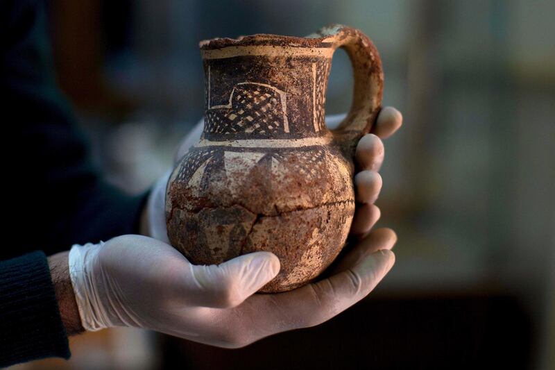 In this Feb. 23, 2016 file photo, Jihad Abu Kahrlah, an archeologist at Syria's National Museum, holds an artifact delivered from the Daraa Museum to Damascus, Syria. Syrian officials have reopened the country's National Museum in Damascus, more than six years after the prominent institution was shut down. Syria's Culture Minister Mohamed al-Ahmad told reporters Sunday, Oct. 28, 2018 that the reopening sends a "genuine message" that Syria's heritage has not been affected by "terrorism." (AP Photo/Hassan Ammar, File)