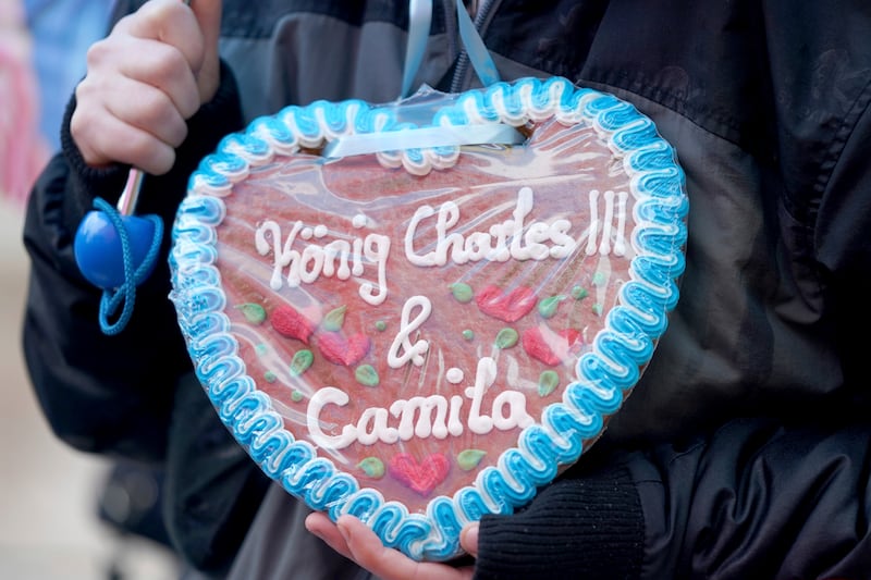 A royal fan carries a gingerbread heart with the inscription "King Charles III & Camila" at Hamburg City Hall. AP