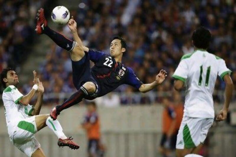 Japan's Maya Yoshida, centre, shoots the ball between Iraq's Waleed Salim, left, and Amjed Radhi Yousuf Al-Janabi.
