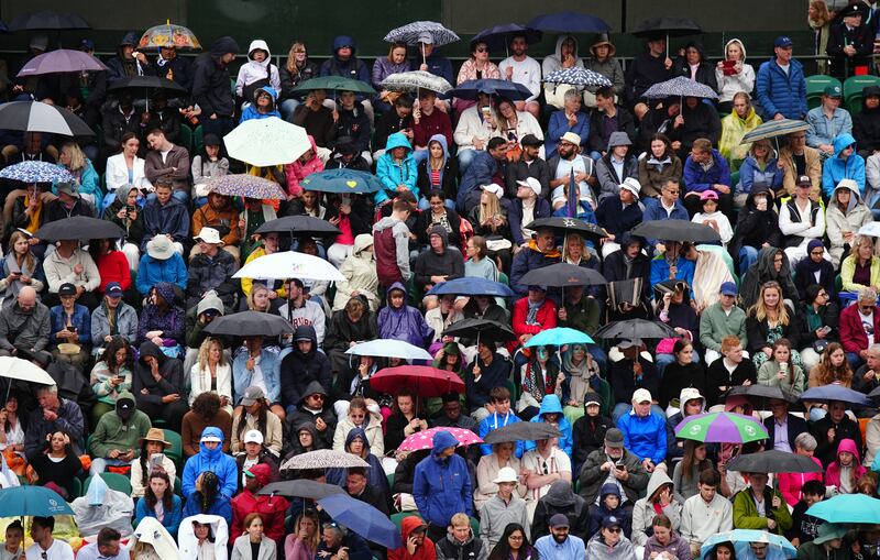 Spectators take shelter from the rain on day three of the 2024 Wimbledon Championships at the All England Lawn Tennis and Croquet Club, London. PA