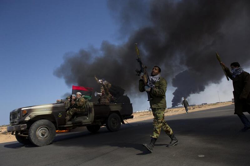 Opposition troops burn tires to use as cover during heavy fighting, shelling, and airstrikes near the  main checkpoint near the refinery in Ras Lanuf as rebel troops pull back from Ras Lanuf, in Eastern Libya, 2011. Courtesy Lynsey Addario
