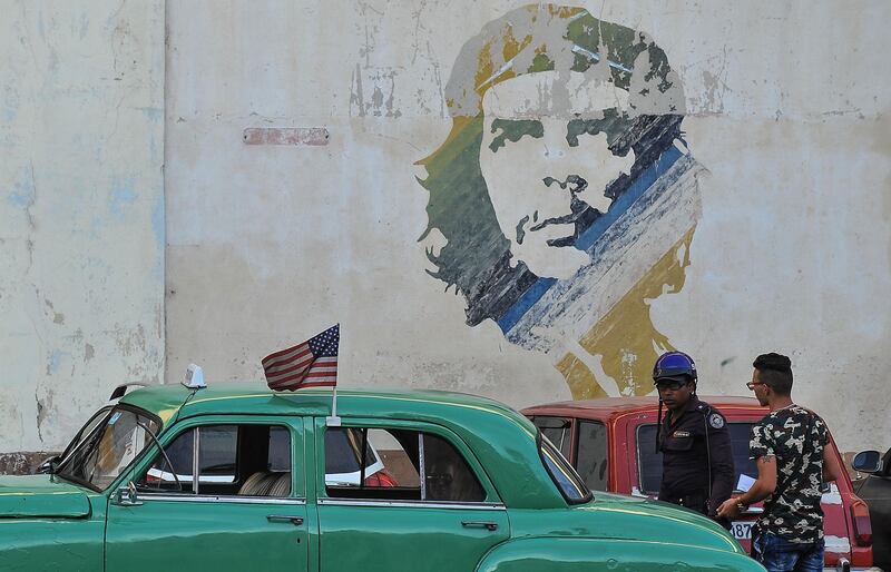 Picture of an old car with a the US flag and a graffiti of revolutionary leader Ernesto 'Che' Guevara.