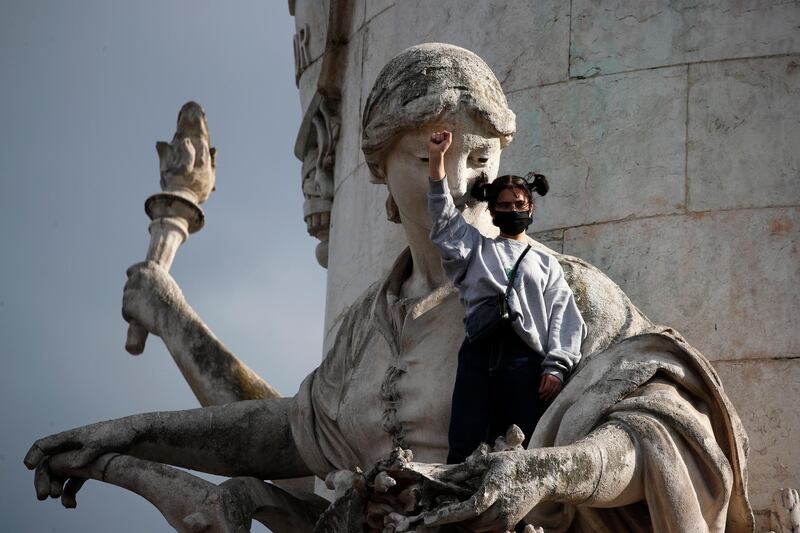 A demonstrator clenches her fist as she stands on a statue on the Place de la Republique during a rally against racism in Paris. AP Photo