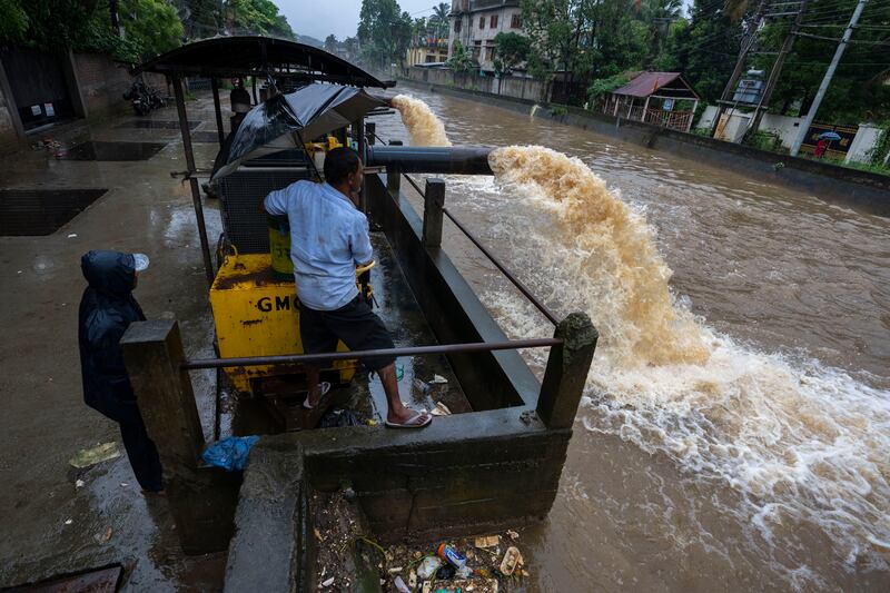 Workers use a pump to remove water from a flooded road in Guwahati. AP 