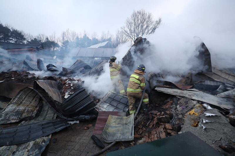 Firefighters put out a fire after a village was swept by the wildfire in Gangneung. Yonhap / Reuters