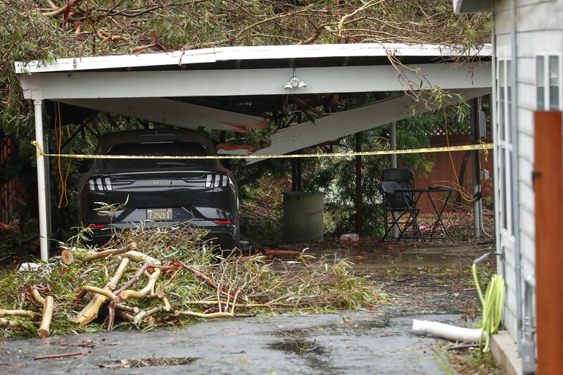 A support beam is split in two, landing on a parked Ford Mach-E after a tall eucalyptus tree fell on a home in the Castro Valley. EPA