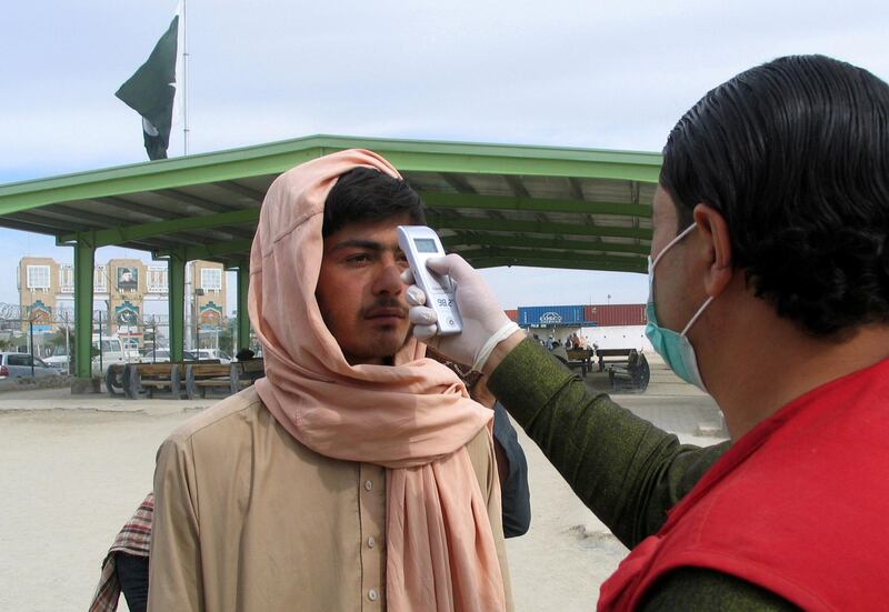 A health worker takes the temperature of a man, who returned from Afghanistan, for a medical observation as a preventive measure following the coronavirus outbreak, crossing point at the Pakistan-Afghanistan border town.  Reuters