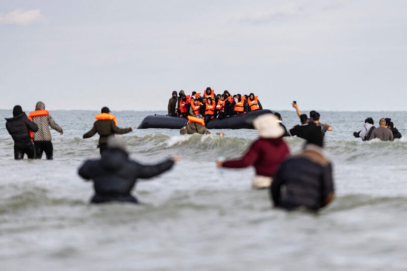 Asylum seekers wave to a smuggler's boat during an attempted crossing of the English Channel from the beach at Gravelines, northern France, three days after five people, including a seven-year-old girl, died while trying make the journey. AFP