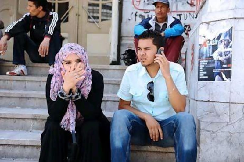 Tunisian youths sit on the steps of a theatre as they pass time while awaiting employment opportunities. Fethi Belaid / AFP