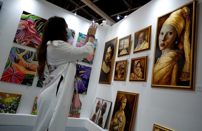 A visitor takes photos at the booth of the L'Atelier Art Gallery of Spain. EPA