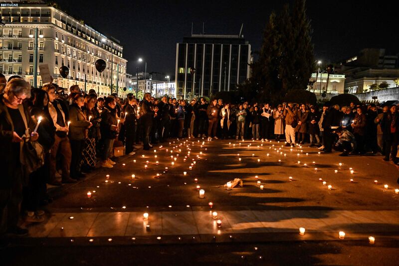 People light candles and hold black balloons during a silent demonstration in front of the parliament in Athens. AFP