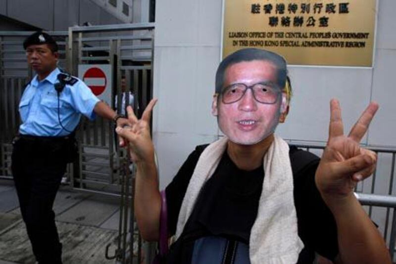 A pro-democracy protester gestures while wearing a mask of Chinese dissident Liu Xiaobo as he and others demand Liu's release outside China's Liaison Office in Hong Kong Monday, Oct. 11, 2010. The imprisoned Chinese dissident who won this year's Nobel Peace Prize was allowed to meet with his wife and told her in tears that he was dedicating the award to victims of a 1989 military crackdown on pro-democracy protesters, his wife and a close friend said.  (AP Photo/Kin Cheung)