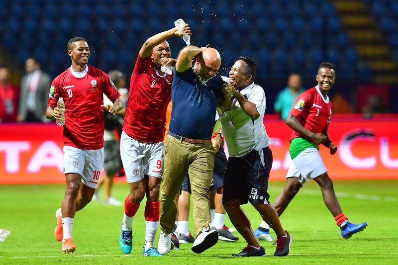Madagascar forwards Faneva Andriatsima, left, and Tsilavina Njiva pour water on  coach Nicolas Dupuis as they celebrate beating Nigeria 2-0. AFP