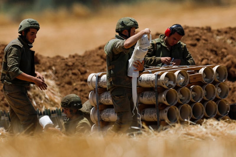 Israeli artillery soldiers prepare propelling charges for a howitzer at the border with Gaza.  EPA