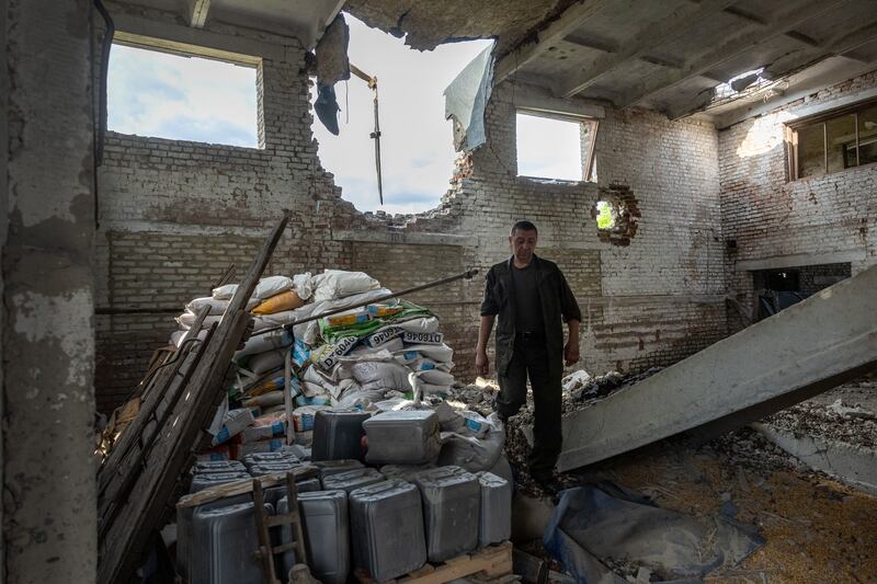 A Ukrainian farm worker walks past grain in a warehouse destroyed by Russian tanks in Cherkska Lozova, Ukraine. Getty Images