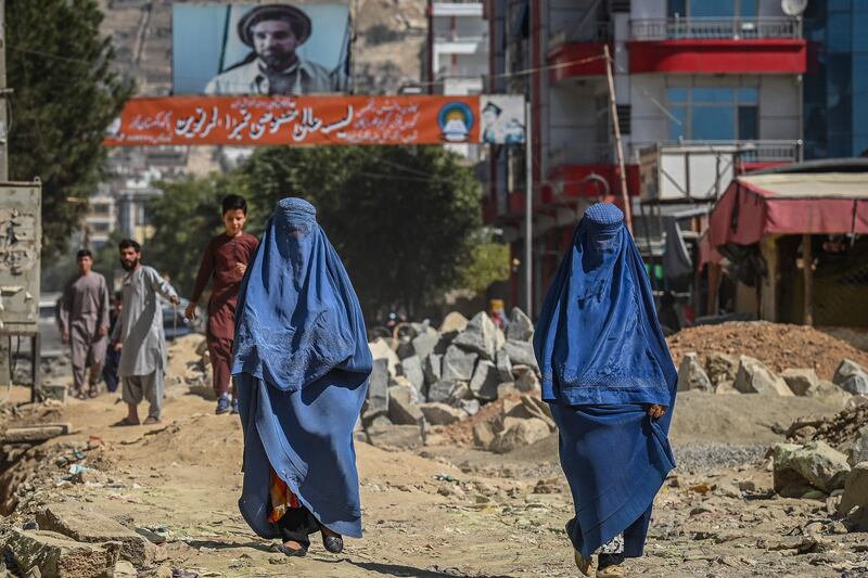 Burqa-clad Afghan women walk along an under-construction road in Kabul. AFP