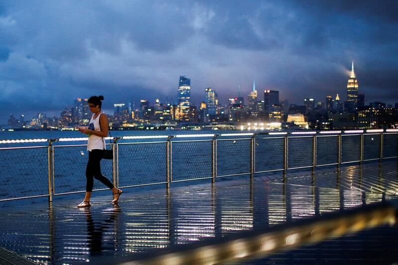 A woman walks on a bridge as low level cloud formation hovers over New York's Empire State Building and the skyline of midtown Manhattan as seen across the Hudson River in Hoboken. Eduardo Munoz / Reuters