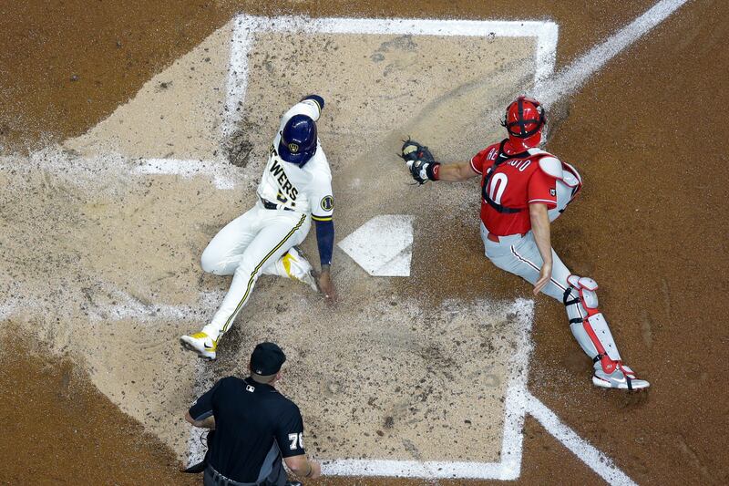 Milwaukee Brewers' Freddy Peralta slides safely past Philadelphia Phillies catcher JT  Realmuto during the MLB game on Wednesday, September 8. AP