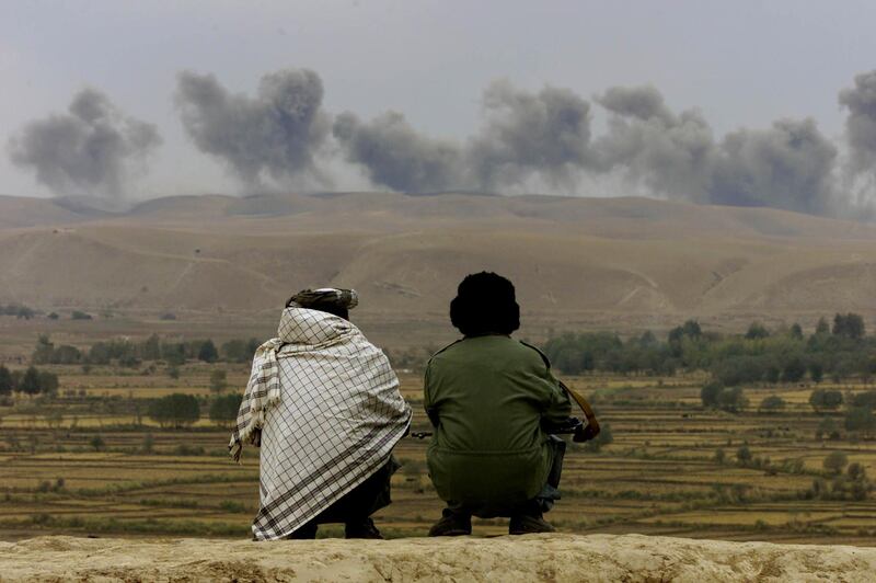 Two Northern Alliance soldiers watch as dust and smoke rise after explosions at Taliban positions on Kalakata hill, near the village of Ai Khanum in northern Afghanistan, November 1, 2001. Reuters