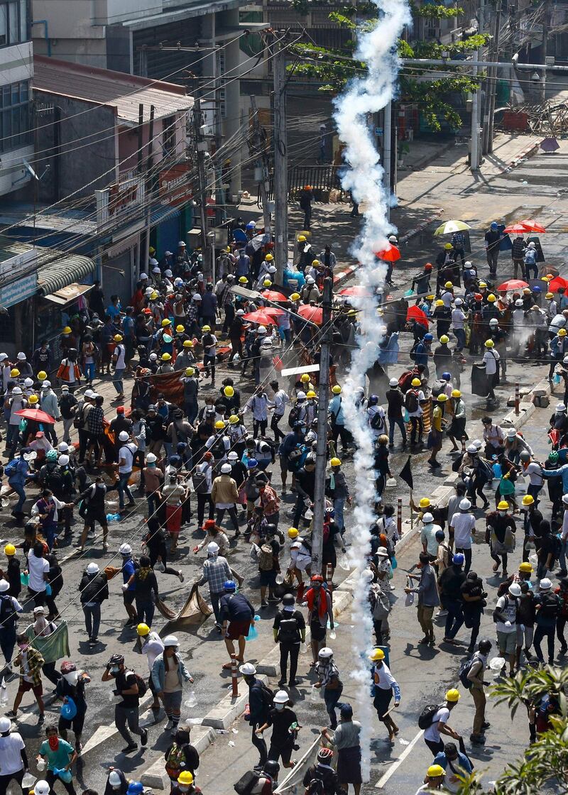 Protesters run as tear gas is fired during a demonstration against the military coup in Yangon.  AFP