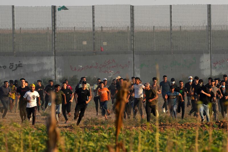 Palestinian protesters run to escape teargas during clashes with Israeli security forces along the frontier with Israel, east of Gaza City on Friday. AP Photo