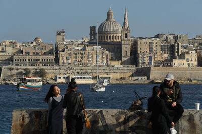 SLIEMA, MALTA - MARCH 29:  Young people relax and photograph each other as Valletta, including the dome of the Basilica of Our Lady of Mount Carmel, stands behind on March 29, 2017 in Sliema, Malta. Valletta, a fortfied town that dates back to the 16th century, is the capital of Malta and a UNESCO World Heritage Site. In the last 2,000 years Malta has been under Roman, Muslim, Norman, Knights of Malta, French and British rule before it became independent in 1964. Today Malta remains a crossroads of cultures and is a popular tourist destination.  (Photo by Sean Gallup/Getty Images)