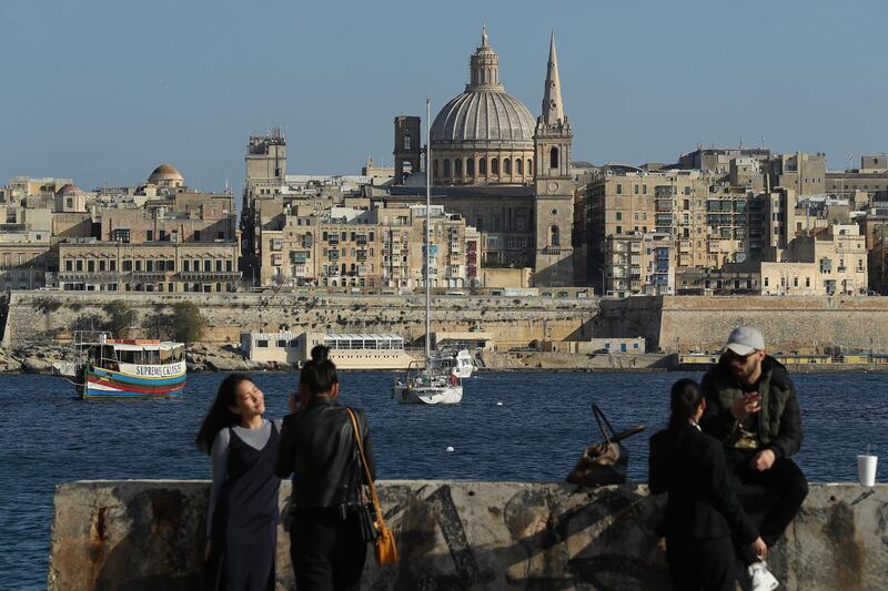 SLIEMA, MALTA - MARCH 29:  Young people relax and photograph each other as Valletta, including the dome of the Basilica of Our Lady of Mount Carmel, stands behind on March 29, 2017 in Sliema, Malta. Valletta, a fortfied town that dates back to the 16th century, is the capital of Malta and a UNESCO World Heritage Site. In the last 2,000 years Malta has been under Roman, Muslim, Norman, Knights of Malta, French and British rule before it became independent in 1964. Today Malta remains a crossroads of cultures and is a popular tourist destination.  (Photo by Sean Gallup/Getty Images)