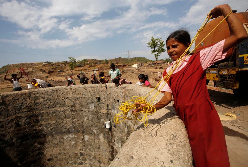 A girl in her school uniform pulls a rope attached to a bucket as she draws water after a tanker emptied water into a dried up well at a village in Maharashtra, India. AP