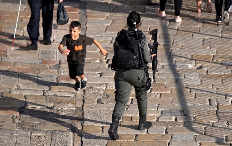 A Palestinian boy runs past an Israeli female border police officer on patroll at Damascus gate of Jerusalem's old city.  EPA