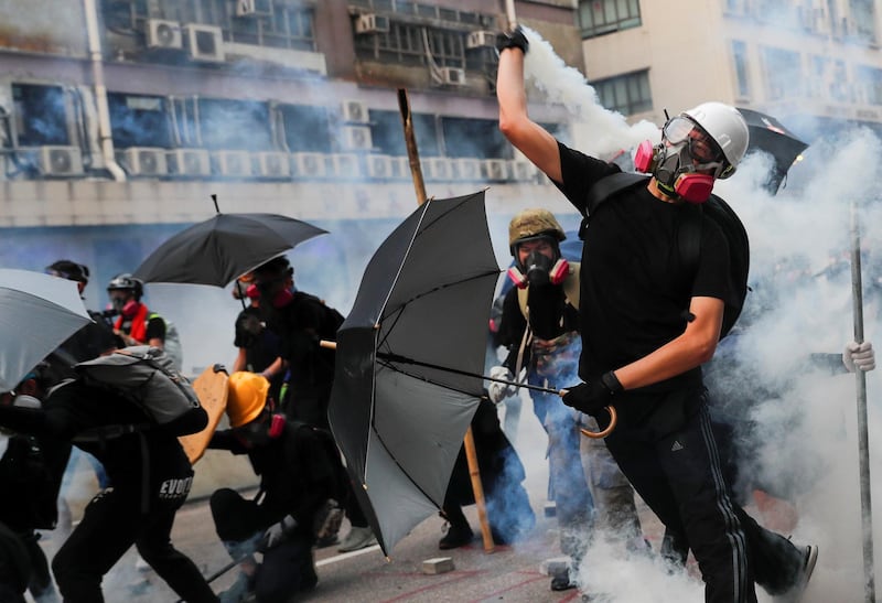 A demonstrator throws back a tear gas canister as they clash with riot police during a protest in Hong Kong. Reuters