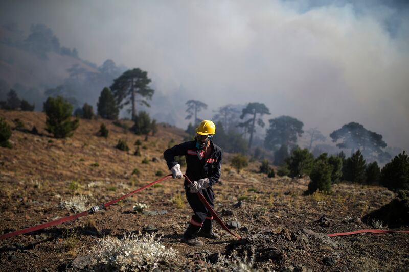 A firefighter adjusts a hosepipe during a bushfire in Mugla, Turkey, in July. AP