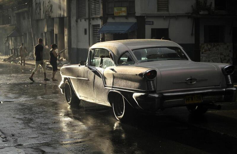 People cross a street as a U.S.-made car, used as a private collective taxi in rain-soaked Havana. Desmond Boylan / Reuters