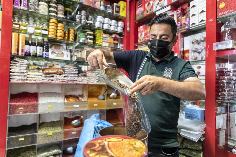 DUBAI, UNITED ARAB EMIRATES. 25 FEBRUARY 2021. COVID - 19 Standalone. Deira souk during the time of Covid. Shop keeper Jalil Ghirban Arshru, fills a bag of tea destined to be sold to tourists. "It's been very tough, with almost no business, and the tourists mainly not coming." (Photo: Antonie Robertson/The National) Journalist: Nick Webster. Section: National.