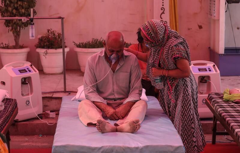 A suspected Covid-19 patient is comforted by a relative as he is given oxygen at a Sikh shrine, or gurdwara, on the outskirts of Delhi, India.