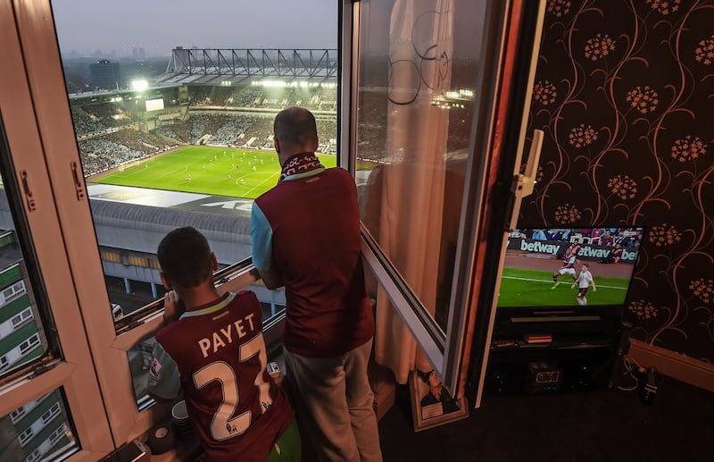A young fan and his father watch from their window as West Ham United play their last ever game at Upton Park, London. 10/05/2016. Michael Regan / FPA / LDY Agency