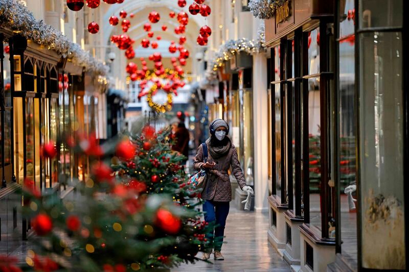 A pedestrian wearing a protective face covering to combat the spread of the coronavirus, walks past Christmas-themed window displays inside Burlington Arcade in central London. AFP