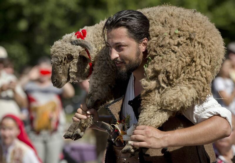 A Bulgarian man carries a ram, offered as a good luck present to a newly wed couple during their wedding in Pchelina, Bulgaria, Sunday, July 6, 2014. Hundreds of Bulgarians on Sunday recreated a 17th century wedding at a folk festival in the northeast of the country. In a spectacular recreation of traditional rituals, a couple got married at the festival in Pchelina, near the city of Razgrad. AP