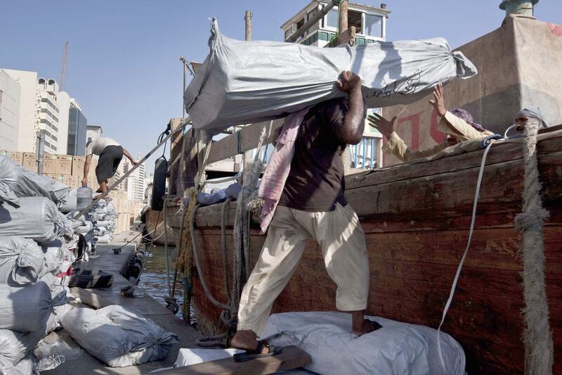 Pakistani labourers load a wooden Cargo dhow bound for Iran with textiles along the loading docks on the Deira side of the creek. Antonie Robertson / The National