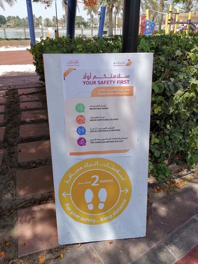 Signage explaining safety guidelines is placed outside Al Barsha Pond Park and its play areas. Katy Gillett / The National