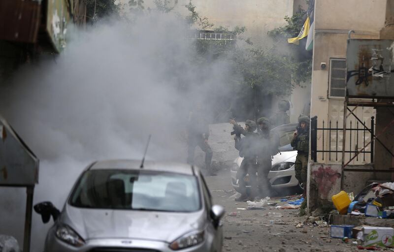 Israeli troops fire tear gas as they clash with Palestinian youth in the Amari refugee camp near Ramallah in the occupied West Bank after they stormed the camp on May 28, 2018.  Israeli troops raided the camp in the early morning hours after Sergeant Ronen Lubarsky, 20, of the Duvdevan special forces unit, reportedly died on May 26, two days after being struck on the head by a stone block thrown during an arrest raid. Israeli media said that the block was a granite slab dropped from a third-floor window. / AFP / ABBAS MOMANI
