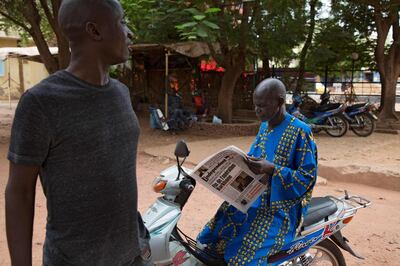 A man buys a newspaper whose headlines announce a major drawdown of France's military presence in the Sahel, where forces have been battling jihadist insurgents for nearly a decade, in Bamako on June 11, 2021. French President announced on June 10, 2021 that the existing Barkhane operation would end, with France's presence becoming part of the so-called Takuba international task force in which "hundreds" of French soldiers would form the "backbone". / AFP / ANNIE RISEMBERG
