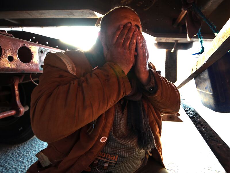 A driver freshens up before driving aid across the border from Egypt